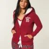 Holiday Vault Release Sherpa-gefütterter Hoodie mit Reißverschluss und Logo-Grafik Holiday Vault Release Sherpa-gefütterter Hoodie mit Reißverschluss und Logo-Grafik