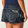 Ultra-niedrige Passform, dunkel gewaschene Denim-Minishorts mit Schmetterlingsstickerei Ultra-niedrige Passform, dunkel gewaschene Denim-Minishorts mit Schmetterlingsstickerei
