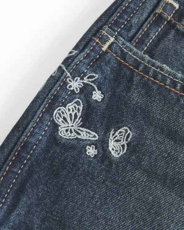 Ultra-niedrige Passform, dunkel gewaschene Denim-Minishorts mit Schmetterlingsstickerei Ultra-niedrige Passform, dunkel gewaschene Denim-Minishorts mit Schmetterlingsstickerei
